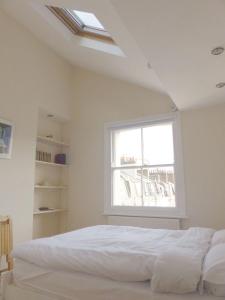 a bedroom with a white bed and a window at Bright, spacious 2 bedroom flat by Russell Square in London