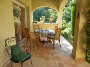 a patio with a table and chairs on a porch at Le Mas de FRAYERE in Le Rouret