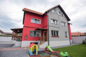 una casa roja y blanca con un patio de juegos en Casa Zia en Făgăraş