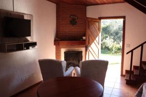 sala de estar con chimenea, mesa y sillas en Chalé Recanto do Sossego en Gonçalves