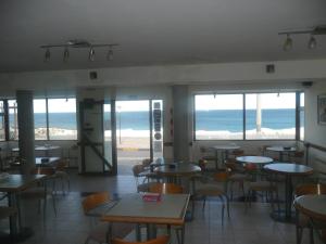 a restaurant with tables and chairs and a view of the ocean at Hotel Riviera in Las Grutas