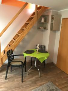 een groene tafel en stoelen in een kamer met een trap bij Gästewohnung Saaleblick in Weißenfels