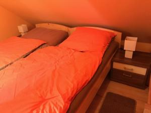 een bed met oranje lakens en een nachtkastje met een bed sidx sidx sidx sidx bij Gästewohnung Saaleblick in Weißenfels