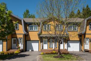 a yellow house with a tree in front of it at Borealis by Rendez-Vous Mont-Tremblant in Mont-Tremblant