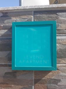 a green sign on top of a stone wall at Levend Apartments in Ksamil