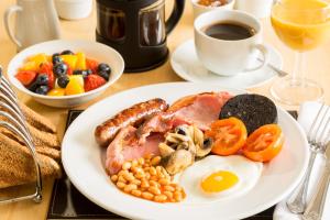 a plate of breakfast food with eggs bacon beans and a cup of coffee at Hermiston Guest House in Keswick