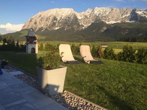 two chairs sitting on a lawn with mountains in the background at Alpenapartments Steiermark in Bad Mitterndorf