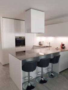 una cocina con armarios blancos y taburetes negros en GaLa Appartamento, en Bellinzona