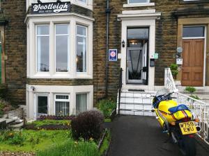 een gele motorfiets geparkeerd voor een huis bij Westleigh in Morecambe