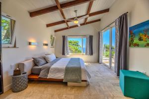 ein Schlafzimmer mit einem Bett, einem Sofa und Fenstern in der Unterkunft Villa Topaz Above West Bay with 360 Degree Views! in West Bay