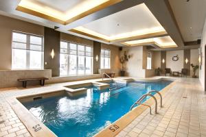 a large pool in a hotel room with a swimming pool at Imperia Hotel & Suites Saint-Eustache in Saint-Eustache