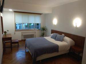 a bedroom with a bed and a desk and a window at La mesa del cocinero in Lugo