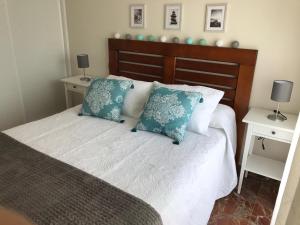 um quarto com uma cama com almofadas azuis e brancas em Céntrico ático junto al mar em Rincón de la Victoria
