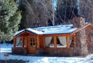 a log cabin with snow on top of it at Cabañas En el Corazón del Bosque in San Carlos de Bariloche