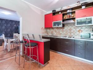 a kitchen with red cabinets and a counter with stools at Apartman Arijana 3 in Medulin