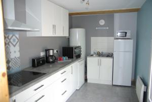 uma cozinha com armários brancos e um frigorífico branco em GRANGE du BOSQUET em Vendeuvre