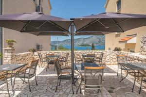 un patio con mesas y sillas bajo una sombrilla en Kis Residence - Adults Only en Korčula