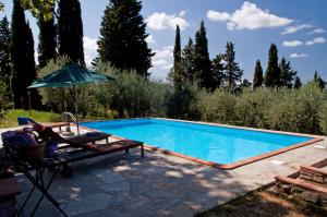 a swimming pool with a chair and an umbrella at Relais Podere Borgaruccio, Wine Resort and Restaurant in Peccioli