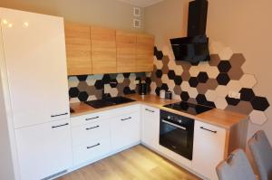 a kitchen with white cabinets and a tv on the wall at Apartament RELAKS w spokojnej okolicy - SUN&SPORT in Szczyrk
