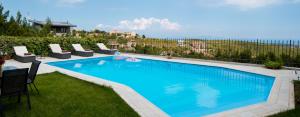 a large swimming pool with lounge chairs at Hillside Villa in Pikérmion