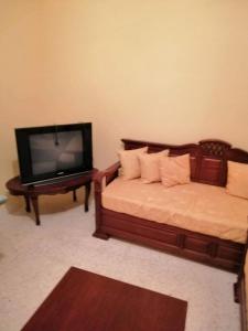 een slaapkamer met een tv en een bed en een tafel bij Maison baha in Hammamet Nord