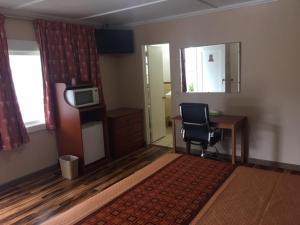 a room with a desk and a chair and a television at Hilltop Inn in Franklin