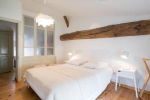 Gite le Pot de Vin في Lancié: غرفة نوم بسرير ابيض وسقف خشبي