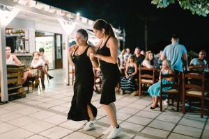 Due donne che ballano sulla pista da ballo di fronte a una folla di Ampavris Family Apartments a Città di Kos