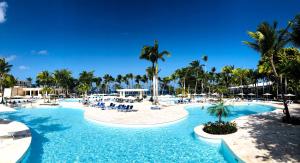 a pool at a resort with chairs and palm trees at Senator Puerto Plata in San Felipe de Puerto Plata