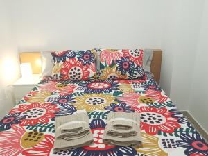 Una cama con una colcha colorida con zapatos. en Moncofa Beach, en Moncófar