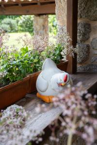 um pato de borracha branco sentado num alpendre com plantas em Casa do Telhado em Guimarães