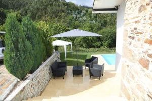eine Terrasse mit Stühlen und einem Sonnenschirm neben einem Pool in der Unterkunft Quinta do Moinho in Castelo de Paiva