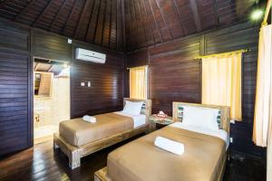 two beds in a room with wooden walls at Agung Lembongan Bungalow in Nusa Lembongan