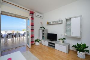 a living room with a television and a balcony at Apartment Milja in Banjol