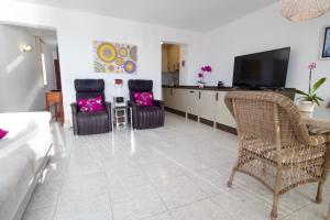 a living room with two chairs and a flat screen tv at Casa al Mar in Puerto de Santiago