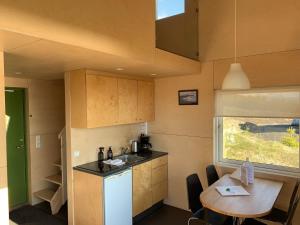 eine Küche mit einem Waschbecken, einem Tisch und einem Fenster in der Unterkunft Sunnuhlid houses in Akureyri