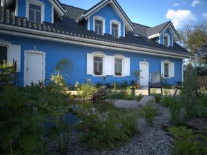 una casa azul con un jardín frente a ella en Pensjonat Krainka en Białowieża