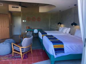 a hotel room with two beds and two chairs at El Blok in Vieques
