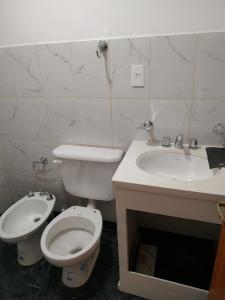 a white bathroom with a toilet and a sink at El Balcón de Sumaj in Maimará
