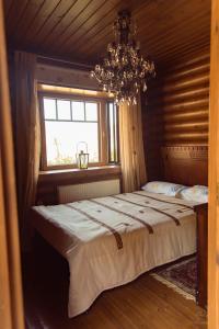 a bedroom with a bed with a chandelier and a window at *2 bdr log house /mountains/Queen bed/fireplace in Gourri