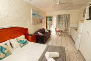 a bedroom with a bed and a couch in a room at Tropical Palms Resort & 4WD Hire in Picnic Bay