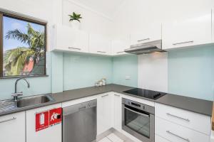 a kitchen with white cabinets and a sink and a window at Byron Bay Accom - Balcony on Lawson in Byron Bay