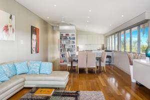 uma sala de estar com um sofá branco e uma cozinha em Byron Bay Accom Unit 1 22 Mahogany Drive - Beach House 1 at Vue em Byron Bay