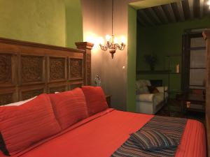 a bedroom with a bed with red sheets and a chandelier at Hotel Galería in San Miguel de Allende