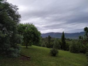 un campo verde con árboles y montañas a lo lejos en Cabañas Altos del Nagual en Valle Hermoso