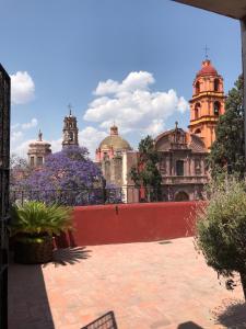 a courtyard with purple flowers and buildings in the background at Hotel Galería in San Miguel de Allende