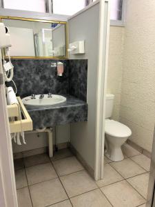 a white toilet sitting next to a sink in a bathroom at Bundaberg Coral Villa Motor Inn in Bundaberg