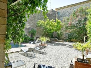 Un patio con sillas y plantas frente a un edificio. en Gîte de l ancienne Poste, en Bourdic