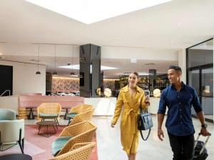 a man and a woman walking through a store at Novotel Sydney International Airport in Sydney