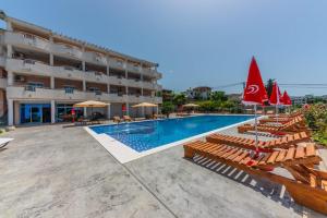 a hotel with a swimming pool with chairs and umbrellas at Apartmani Djurovic in Dobra Voda